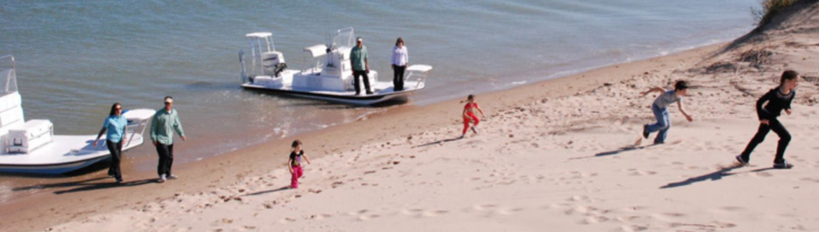 The Sportsman, two boat pulled up to a beach with families starting their fun.