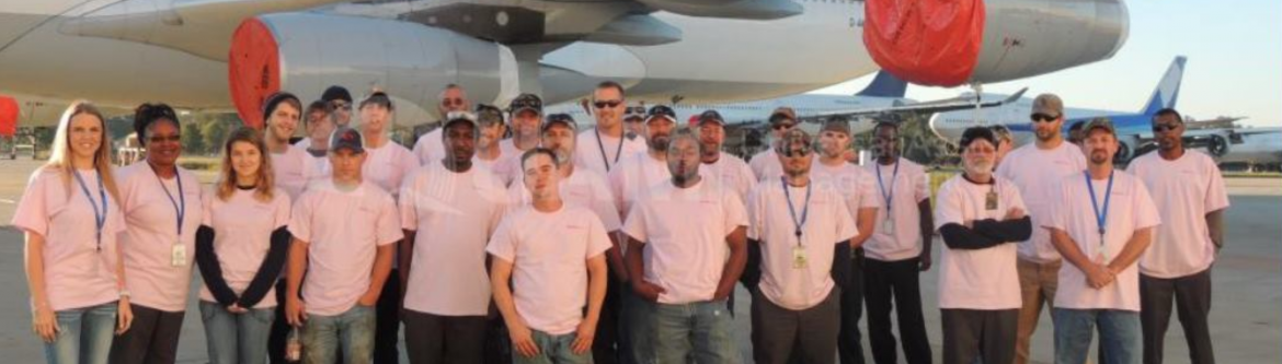 Universal Asset Management group of employees posing in front of a jet.