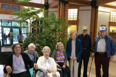 Mission Oaks residents post for a photo in the front lobby with a tree behind them.