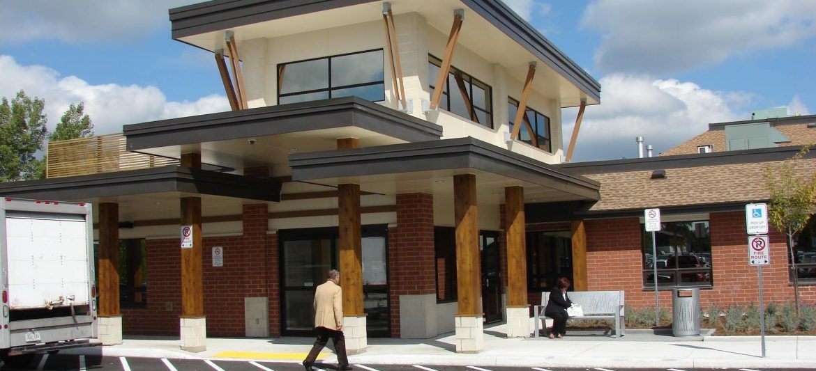 Dependable Mechanical Solutions. Front entry to a building with a man walking towards the door and a work vehicle parked to his left.