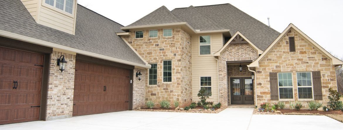 Heritage Custom Homes. The front of a house with two garage doors on the left.