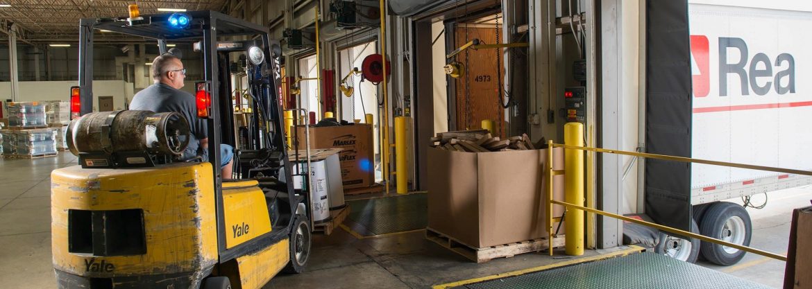 A forklift loading materials onto an Rea Magnet Wire truck.