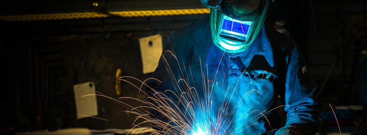 Ebner Furnaces Inc. A man welding with protective mask and clothing on.