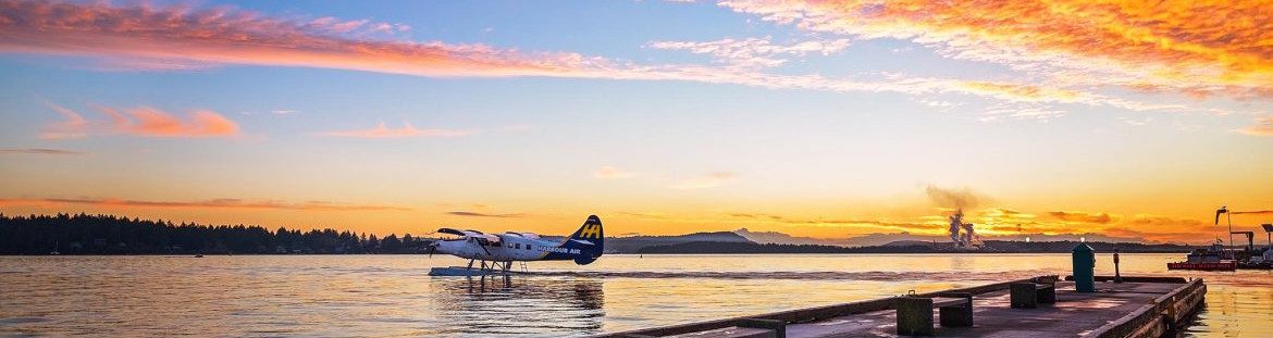 Nanaimo British Columbia. A plane under way on the water, an orange and blue sky in the background and a dock in the foreground.