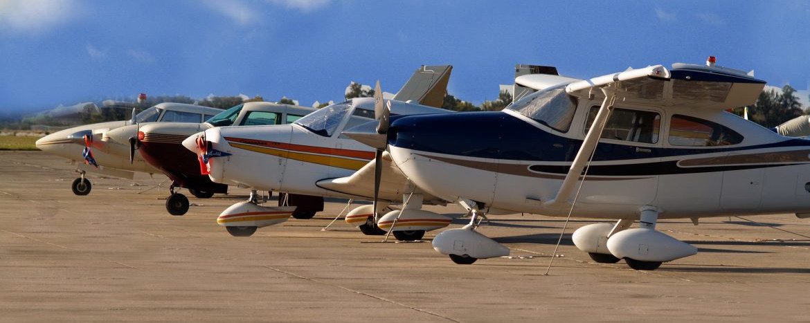 Sebring Regional Airport & Commerce Park with a row of single prop planes in a row on the tarmac.