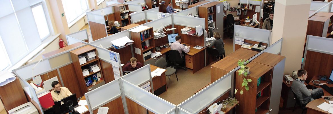 Ceiling view of an office full of cubicles and working employees at their desks.
