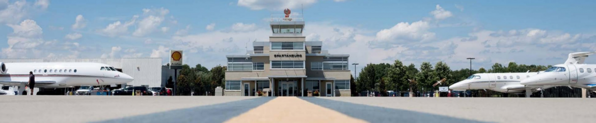 Spartanburg Downtown Memorial Airport view of the control tower down the runway with planes on either side.
