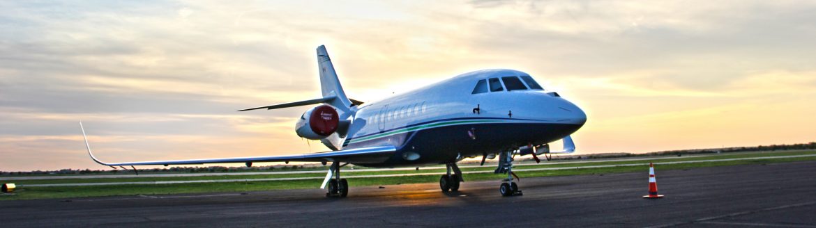 Stillwater Regional Airport. A Jet on a runway with the sun and clouds behind it.