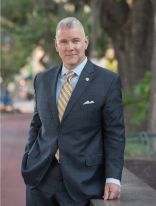 Leon County Florida Administrator Vince Long standing in a suit.