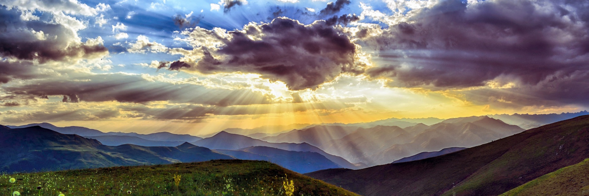 United States Environmental Protection Agency. Green hills with a beautifully colored sky, clouds and sun covered by a cloud but the suns rays peaking below.