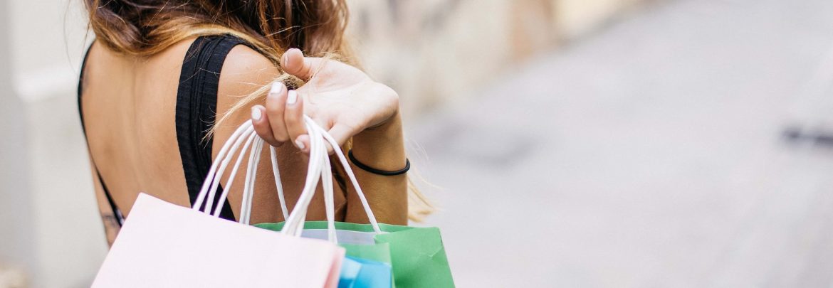 A woman with her hand holding shopping bags over her shoulder.