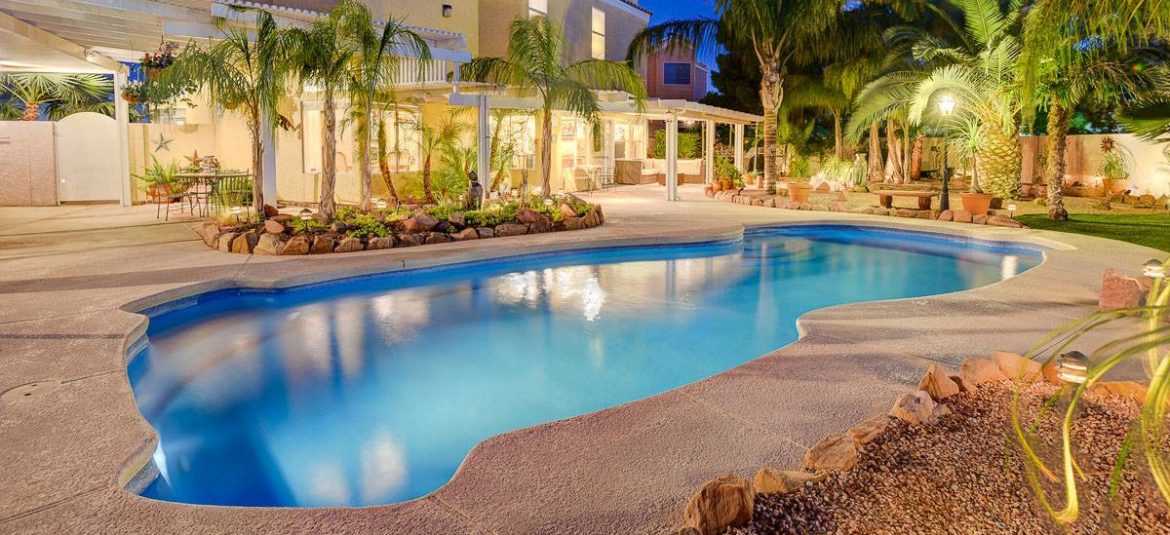 Latham Pool Products Inc. example of work showing a pool with a light on inside of it and palm trees in the landscaping.