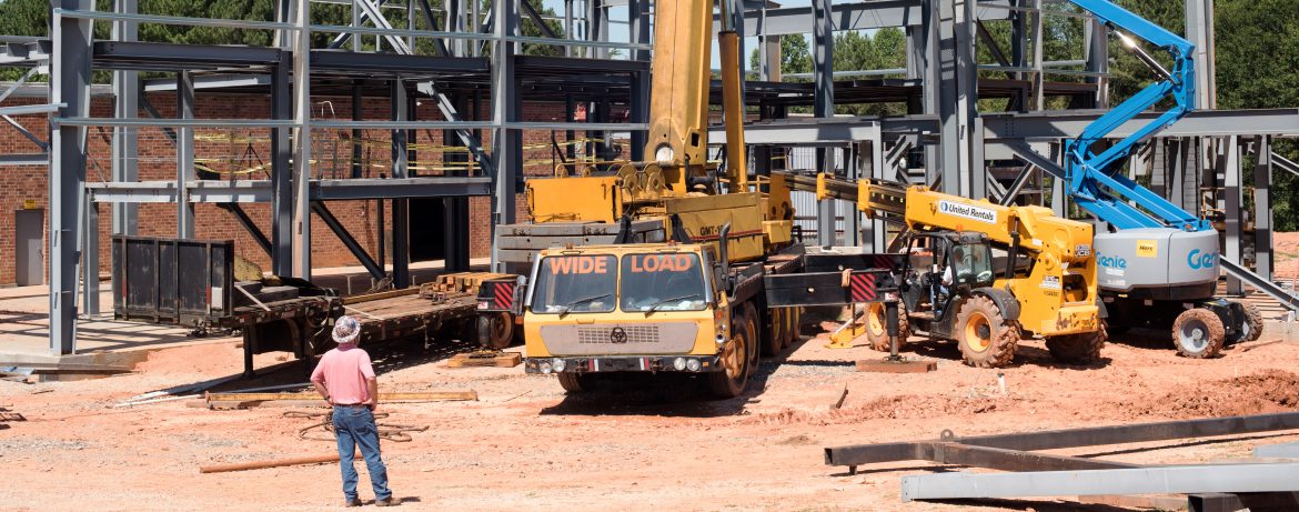 Mafic work site with multiple work vehicles including lifts and cranes.