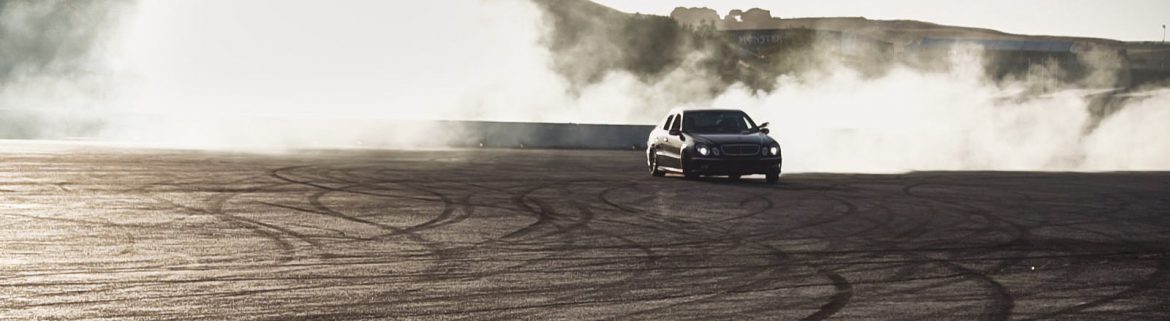 FCP Euro. A race car smoking tires in a large open paved area.