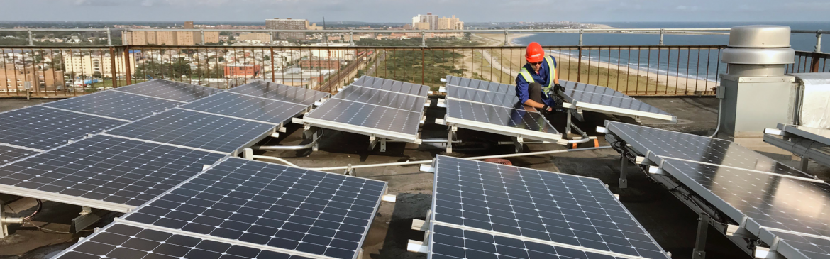Bright Power. A man working on solar panels on top of a flat roof.