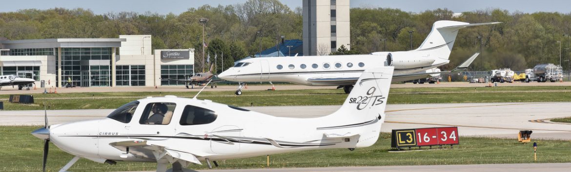 Chicago Executive Airport. Two planes on the runway with the airport control tower behind.