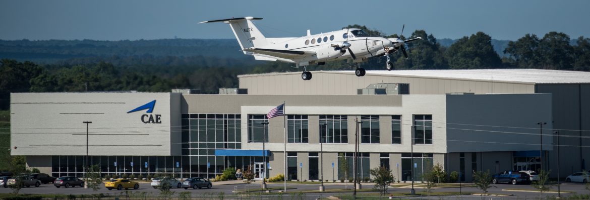 Dothan Regional Airport, a single prop plane flying by the airport building.