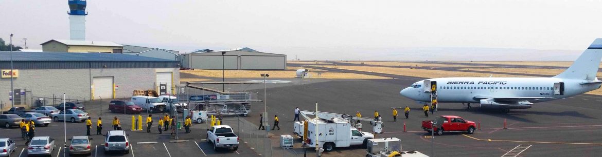 Lewiston-Nez Perce County Regional Airport. View of building, vehicles parked and an passenger jet on the right.