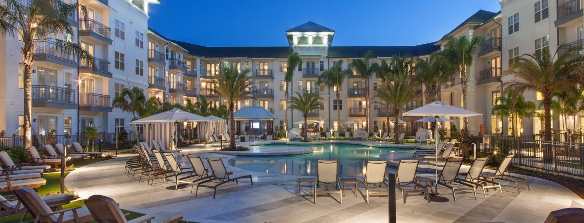 ZRS Management. Large residential multi unit building, view of the pool area with the building around it.