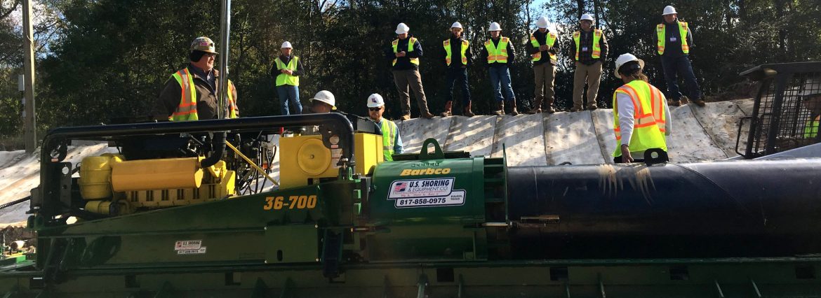 Barbco Inc. Boring machine with workers in yellow vests and hard hats near.
