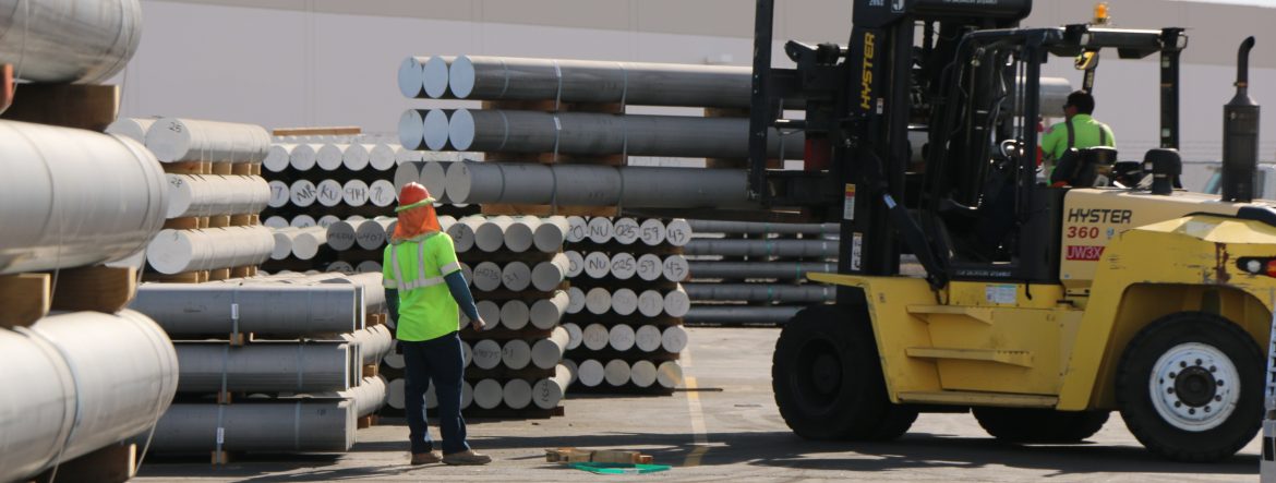 MHX Solutions cylinder shaped metal ingots being moved by forklift.