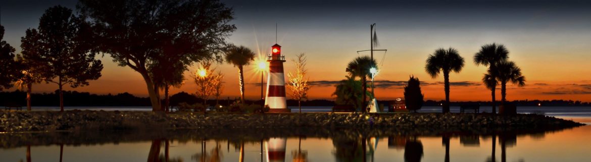Mount Dora Florida, sunset view with a lighthouse, palm trees and an orange sky.