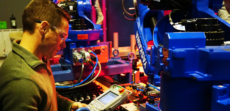 BOS Innovations employee at work with a handheld device next to equipment.