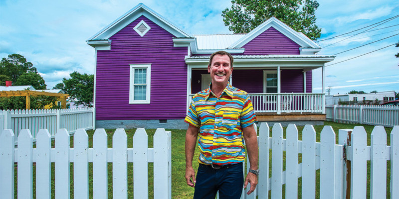 Kinston, North Carolina. Steph Hill standing by a white picket fence in front of a house.