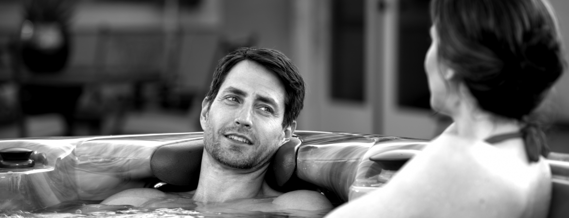 A man and woman in a hot tub, black and white photo. MAAX Spas.