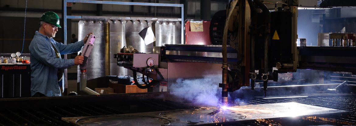 A worker for Fisher Tank Company operates a cutting machine.