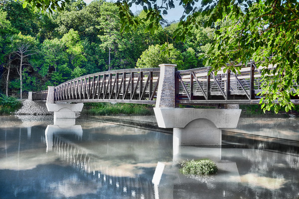 Logansport, Indiana Cole Bridge stretching over the river with calm water and clouds reflecting on the water.
