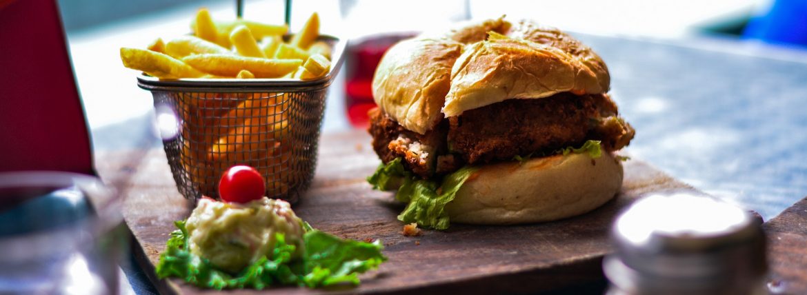 A burger and fries at a restaurant. Look for Calorie information when eating out.