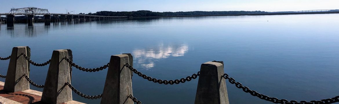 Beaufort, South Carolina, SC image of a body of water with a truss bridge in the background on the left and a walkway in the foreground.
