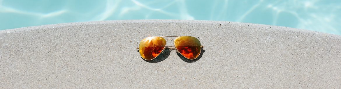 Sunglasses sitting on the edge of a pool, view from above. Town and Country San Diego.