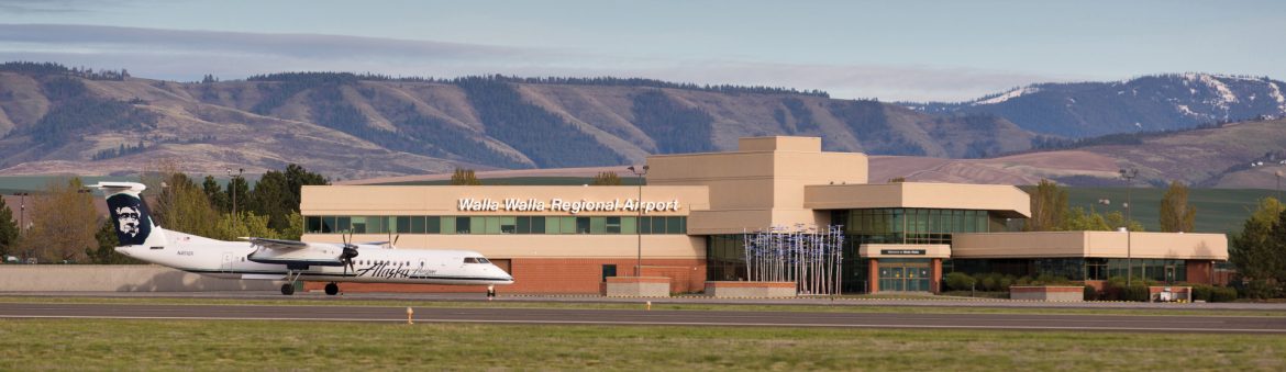Walla Walla Regional Airport terminal building with a jet out front and mountains behind.