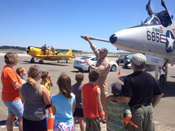 Evansville Regional Airport photo of a pilot standing in front of a fighter plane in front of adults and children talking.