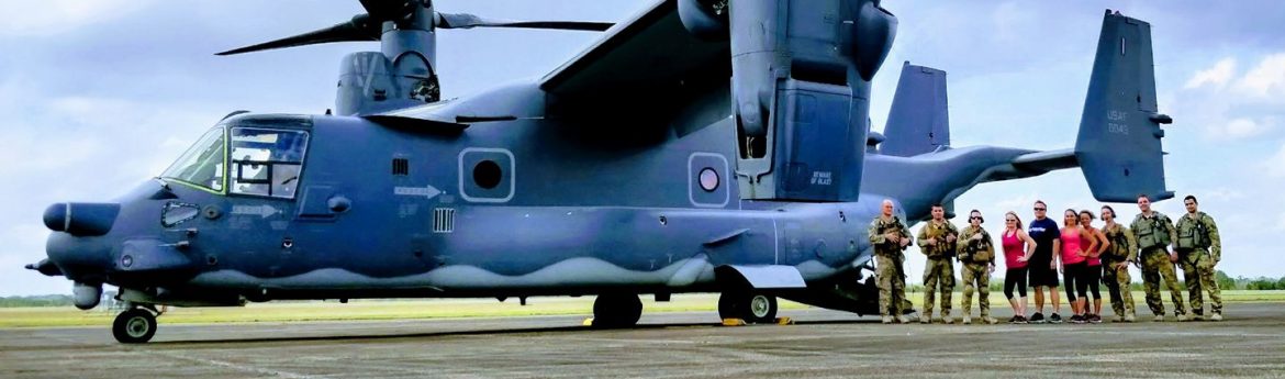 Marianna Municipal Airport runway with a group of people to the right of a military plane that does vertical takeoffs.