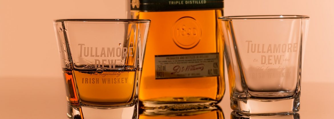Tullamore Dew Irish Whiskey bottle and two glasses on a table top. Top Executive Brands - Irish Whiskey.