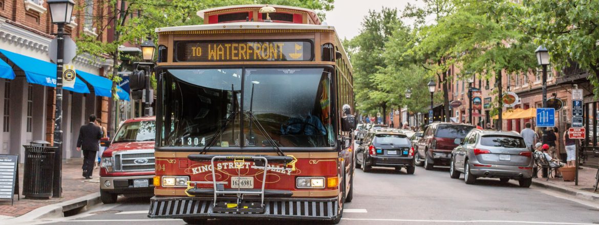 Alexandria Transit Company bus on the street with businesses and cars.