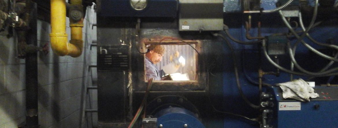 California Boiler employee Ernie Hidalgo inside of a boiler looking at papers with a flashlight in hand.