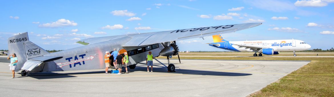 Punta Gorda Airport runway with an old propr plane on the left and an Allegiant commercial jet on the runway behind.
