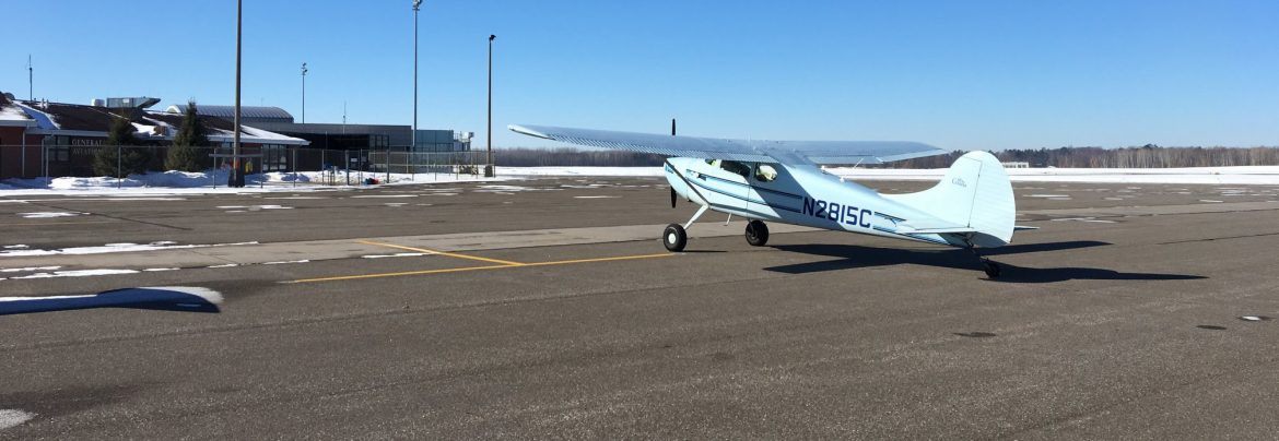 Brainerd Lakes Regional Airport runway with a small plane and snow around the building.