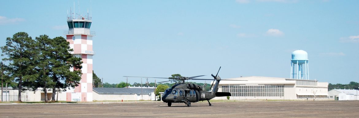 Craig Field Airport buildings showing the control tower and a water tower, with a helicopter in the middle.