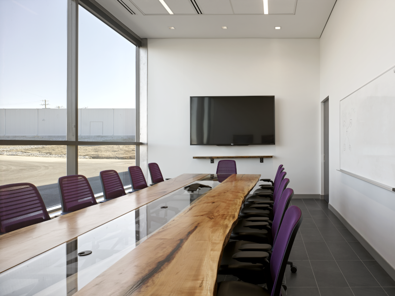 SvN Architects & Planners meeting room / board room with tv on the wall and a nice natural wood conference table with glass down the middle.