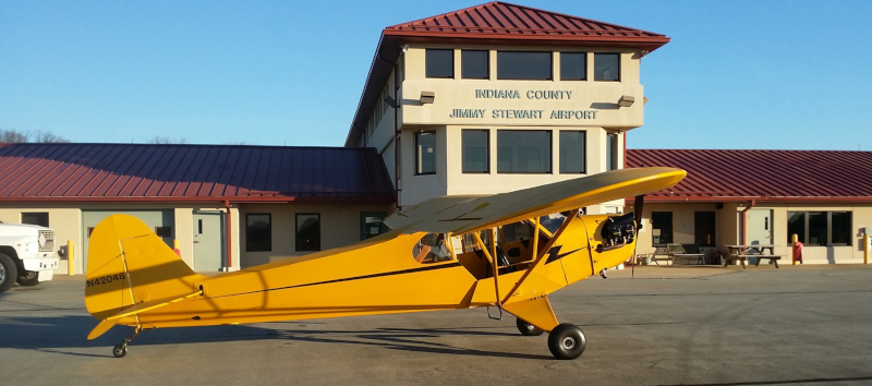 Indiana County Jimmy Stewart Airport runway side of terminal with a yellow cub airplane.