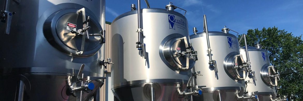 Quality Tank Solutions tanks loaded on a truck for delivery with blue sky behind.