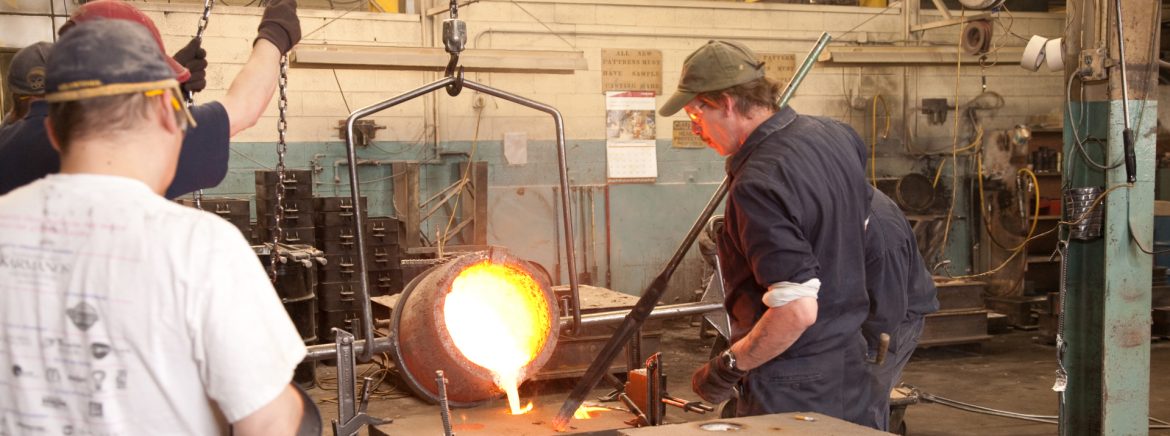 Wolverine Bronze Co. employees pouring molten metal into a mold.