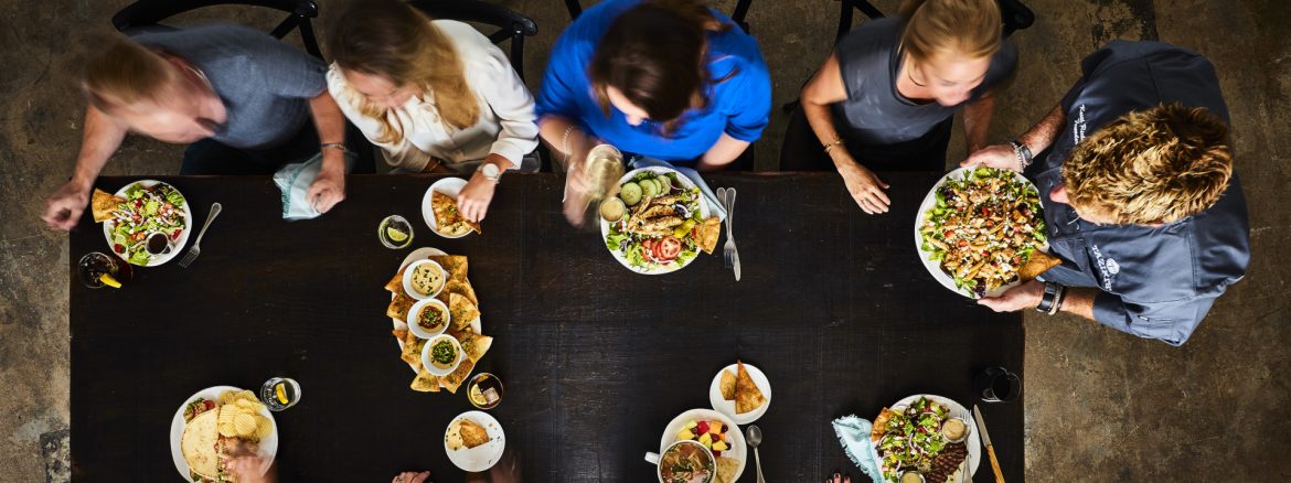 Taziki’s Mediterranean Café community table view from above with a waiter serving people at a table.