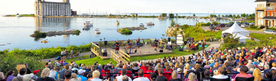 Collingwood, Ontario event with a crown sitting watching musicians along the water.