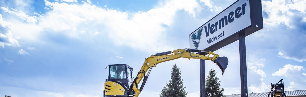 Vermeer Midwest sign and a woman operating a Vermeer excavator next to it.